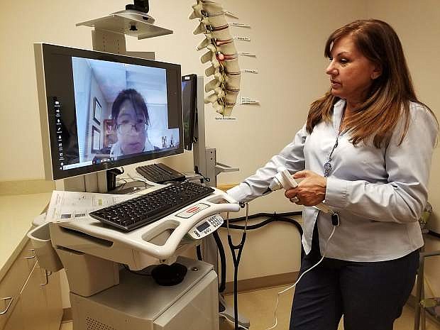 Corie Nieto, director, telehealth services, Nevada Health Centers, talks with Dr. Betsy Huang, a Las Vegas-based pediatrician using a telehealth cart.