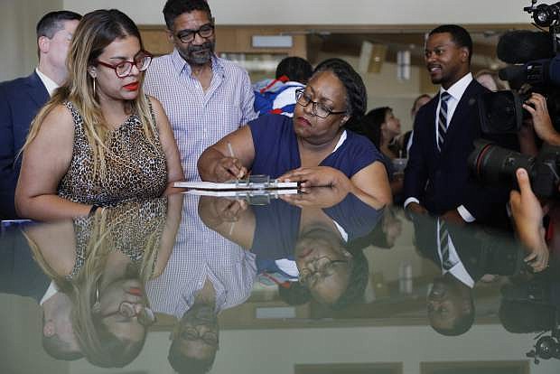 Ora Watkins, center, registers to vote following a news conference Monday, July 1, 2019, in North Las Vegas, Nev. Watkins became eligible to vote when a law that automatically restores the right to vote for formerly incarcerated individuals took effect Monday in Nevada. (AP Photo/John Locher)