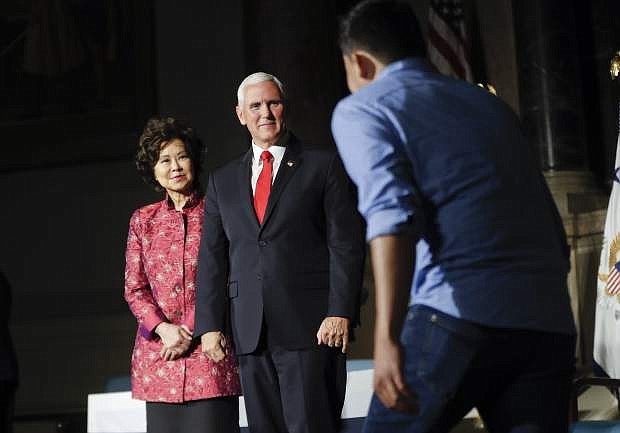 Vice President Mike Pence, center, and Transportation Secretary Elaine Chao, left, greet on stage a new naturalized citizens during a naturalization ceremony in celebration of Independence Day at the National Archives in Washington, Thursday, July 4, 2019. (AP Photo/Pablo Martinez Monsivais)