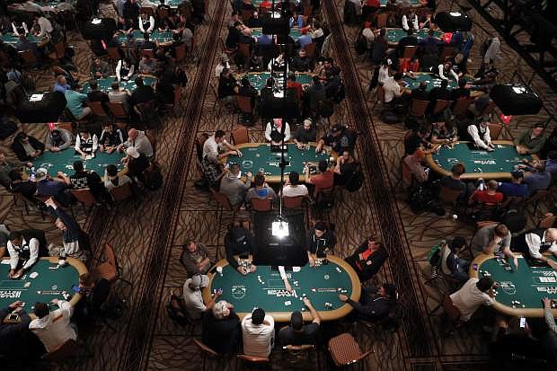 FILE - In this June 24, 2019, file photo, players and dealers sit at tables during a tournament at the World Series of Poker in Las Vegas.T ens of thousands of professional and amateur poker players go on a pilgrimage to Las Vegas every summer in hopes of returning home richer, owning a gold bracelet and earning considerable bragging rights. They all want to win at the World Series of Poker. The tournament is marking its 50th year. The $10,000 buy-in, no-limit Texas Hold &#039;em main event kicks off Wednesday, July 3. (AP Photo/John Locher, File)
