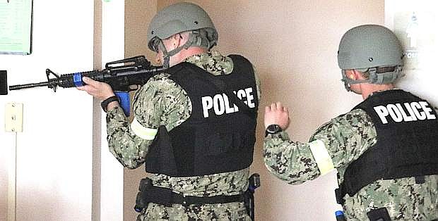 During a practice drill prior to July, security police officers check out the base theater an evaluator watches.