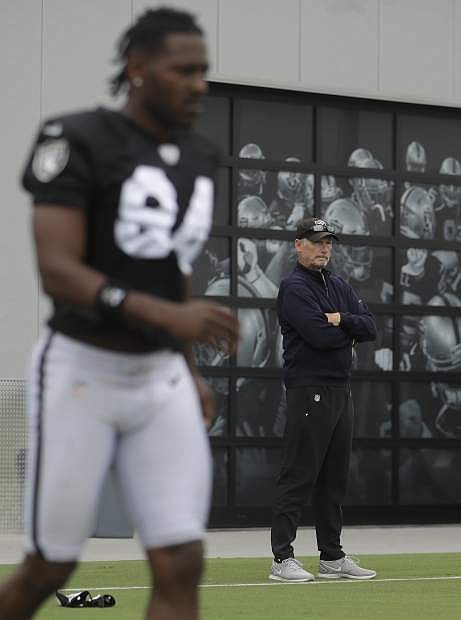 Oakland Raiders general manager Mike Mayock, right, watches while players stretch as Antonio Brown (84) walks on the field during NFL football practice in Alameda, Calif., Tuesday, Aug. 20, 2019. (AP Photo/Jeff Chiu)