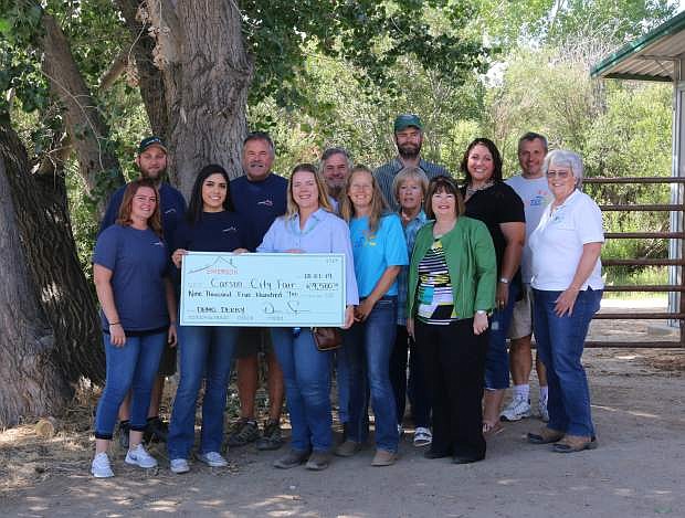 Simerson representatives, in blue shirts, who hosted the Demolition Derby, stand with Active 20-30 Club president Timothy Provost (red vest) and club members. The club donated $1,405.85 to the Carson City Fair. Simerson Events provided $9,500 to the fair.