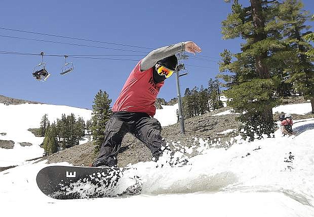 FILE - In this July 1, 2017 file photo, a snowboarder cuts throughout the snow at the Squaw Valley Ski Resort in Squaw Valley, Calif. A proposal to connect two Lake Tahoe ski resorts with a 2.2-mile-long (3.5-kilometer-long) gondola has moved closer to final approval. Placer County&#039;s approval of the project on Tuesday is one of the &quot;last crucial steps&quot; toward linking Squaw Valley and Alpine Meadows, said Ron Cohen, president of Squaw Valley Alpine Meadows. The Sierra Sun reports the gondola with eight-passenger cars would transport up to 1,400 people an hour on a 16-minute trip between the bases of the co-owned, neighboring resorts northwest of Tahoe City, California. (AP Photo/Rich Pedroncelli, File)