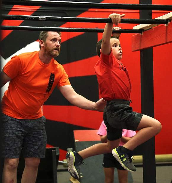 Samuel Papez, 7, attacks the second jumping bar with a little assistance from Sensei Chris Hadlock at the Kids Ninja Warrior obstacle course located at 900 Mallory Way. The course will have its official grand opening toward the end of October.