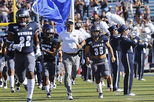 Nevada coach Jay Norvell, center, leads his team onto the field to face Weber State for an NCAA college football game in Reno, Nev., Saturday, Sept. 14, 2019. (AP Photo/Lance Iversen)