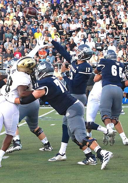 Nevada quarterback Carson Strong (12) gets the pass off against a persistent Purdue defense.