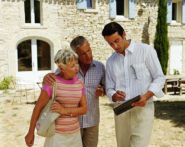 Man showing paperwork to couple outside house
