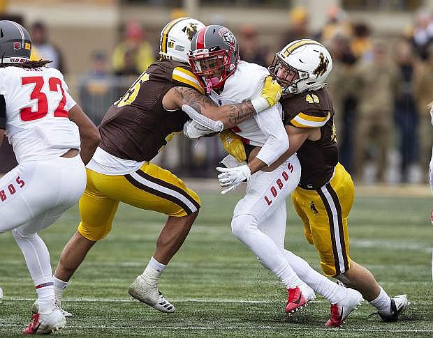 New Mexico&#039;s De&#039;John Rogers is hit by Wyoming defenders Jaylon Watson, left, and Chad Puma during a game Oct. 19 in Laramie, Wyoming.