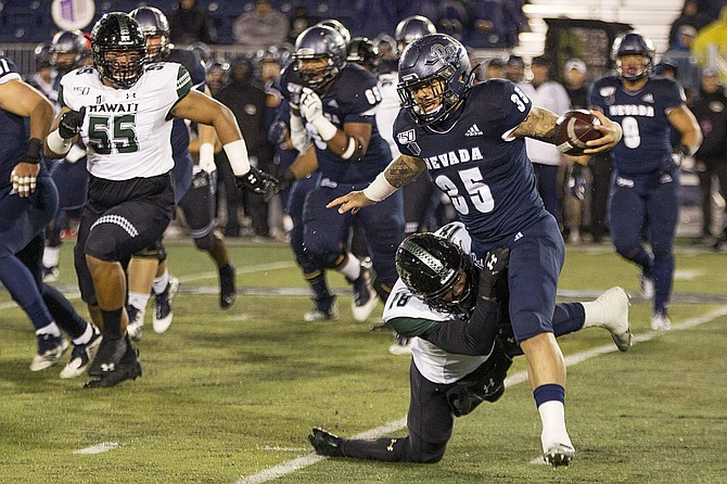Nevada running back Toa Taua (35) is grabbed by Hawaii&#039;s Cortez Davis (18) in the first half of an NCAA college football game in Reno, Nev., Saturday, Sept. 28, 2019. (AP Photo/Tom R. Smedes)