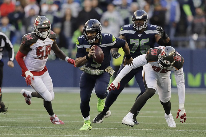 Seattle Seahawks quarterback Russell Wilson (3) scrambles away from Tampa Bay Buccaneers defensive end Jason Pierre-Paul (90) during overtime of an NFL football game, Sunday, Nov. 3, 2019, in Seattle. (AP Photo/John Froschauer)