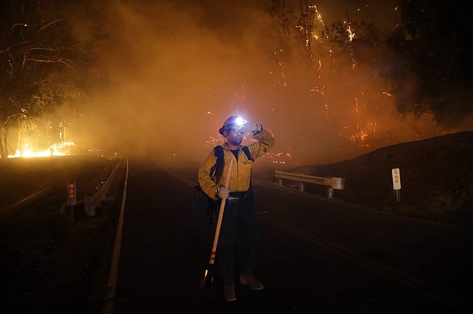 A firefighter stands on a road as the Maria Fire burns behind him Friday, Nov. 1, 2019, in Somis, Calif. (AP Photo/Marcio Jose Sanchez)