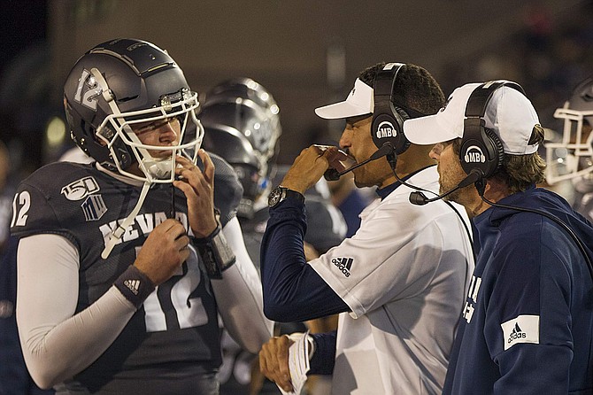 Former Nevada head coach Jay Norvell, center, and former Wolf Pack offensive coordinator Matt Mumme, right, talk with quarterback Carson Strong during a game against New Mexico. Norvell and Mumme are both heavily influenced by Mike Leach's Air Raid offensive philosophy.