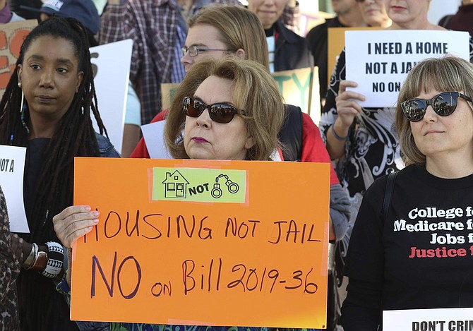 Eva Love, left, and Deidre Radford of Las Vegas hold signs outside Las Vegas City Hall as they protest against the city council&#039;s ban on homeless camping on Wednesday, Nov. 6, 2019, in Las Vegas. Officials passed a law Wednesday making it illegal for the homeless to sleep on streets when beds are available at established shelters.  (Bizuayehu Tesfaye /Las Vegas Review-Journal via AP)