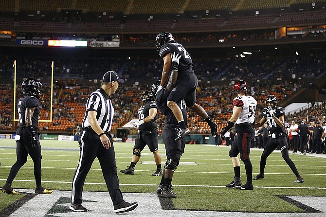 Hawaii offensive lineman Gene Pryor lifts running back Fred Holly III after Holly III scored a touchdown against San Diego State on Saturday in Honolulu.