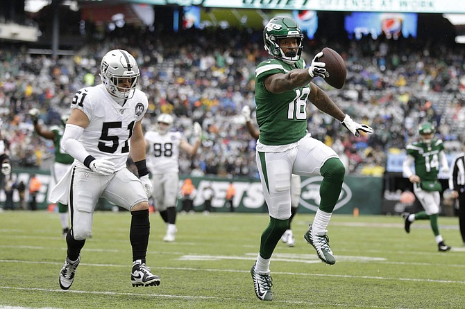 ADDS THAT THE TOUCHDOWN WAS LATER NULLIFIED BY PENALTY - New York Jets wide receiver Demaryius Thomas (18) runs away from Oakland Raiders inside linebacker Will Compton (51) for a touchdown during the first half of an NFL football game Sunday, Nov. 24, 2019, in East Rutherford, N.J. The touchdown was later nullified by penalty. (AP Photo/Adam Hunger)