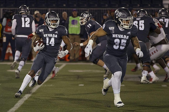 Nevada wide receiver Dominic Christian (14) follows the block of running back Toa Taua against New Mexico on Saturday at Mackay Stadium in Reno.