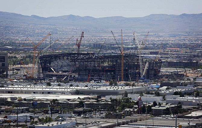 FILE - In this June 4, 2019, file photo, construction cranes surround the football stadium under construction in Las Vegas. The new $2 billion stadium being built near the Las Vegas Strip for the NFL&#039;s Oakland Raiders is not expected to have a roof in place until April but should be finished in summer. Don Webb, the chief operating officer of a Raiders subsidiary that&#039;s building the stadium, said the facility is still expected to be finished July 31. (AP Photo/John Locher, File)