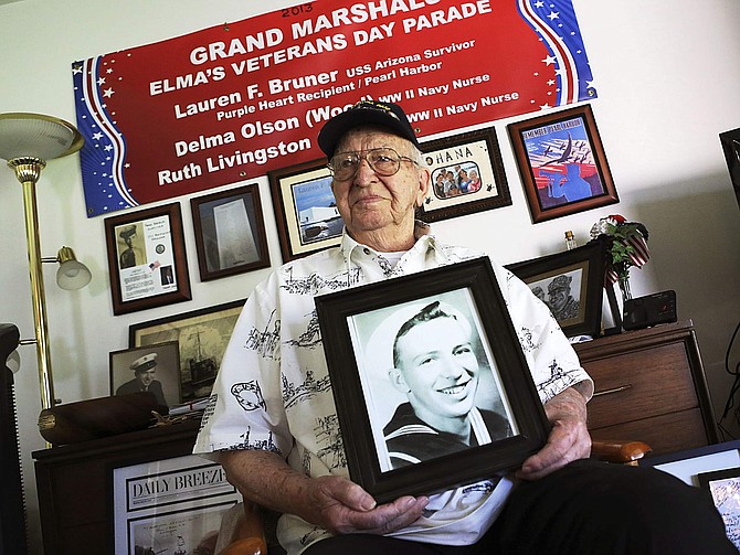 FILE - In this Nov. 17, 2016, file photo, Lauren Bruner, a survivor of the USS Arizona which was attacked on Dec. 7, 1941, holds with a 1940 photo of himself at his home in La Mirada, Calif. Divers will place the ashes of Bruner in the wreckage of his ship during a ceremony this weekend in Pearl Harbor, Hawaii.   Bruner died earlier in 2019 at the age of 98. (AP Photo/Reed Saxon, File)