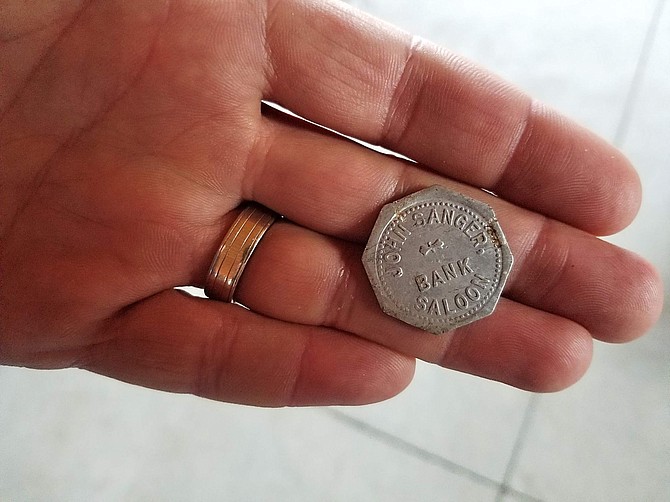 Aaron West, CEO, Nevada Builders Association, holds a Bank Saloon token, one of the few artifacts found during renovation.