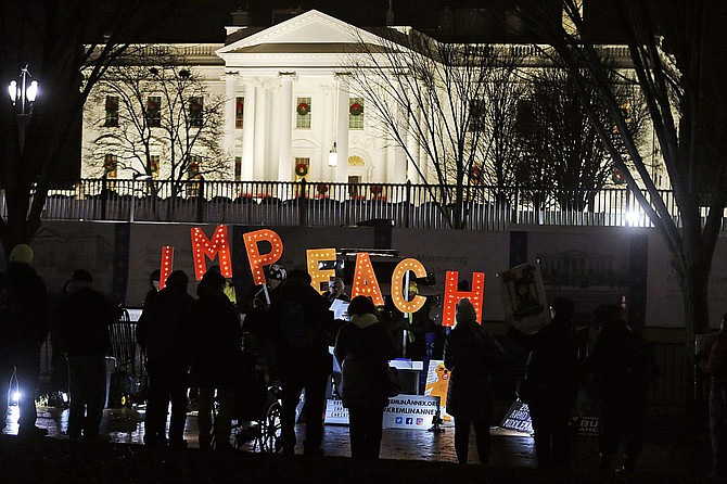 Protesters hold signs and sing in front of the White House Tuesday, Dec. 17, 2019 in Washington. (AP Photo/Steve Helber)