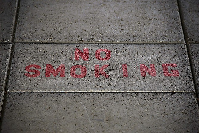 No smoking painted on a sidewalk right next to a gas pump