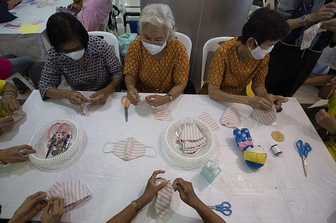Volunteers assemble cloth masks for free at the Ministry of Social Development and Human Security in Bangkok, Thailand, Wednesday, March 11, 2020. For most people, the new coronavirus causes only mild or moderate symptoms, such as fever and cough. For some, especially older adults and people with existing health problems, it can cause more severe illness, including pneumonia. 