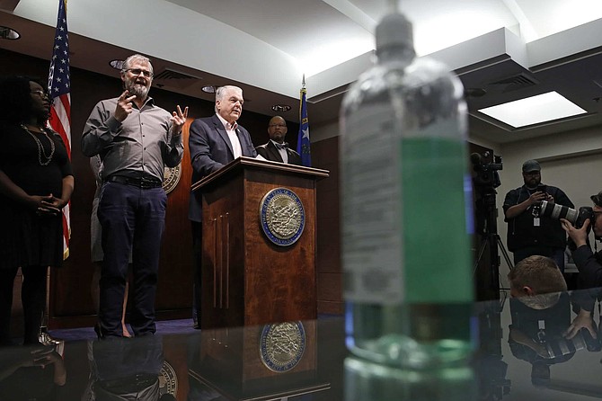 With a bottle of hand sanitizer on a table nearby, Nevada Gov. Steve Sisolak announces a state of emergency amid coronavirus fears, at a news conference Thursday, March 12, 2020, in Las Vegas. (AP Photo/John Locher)
