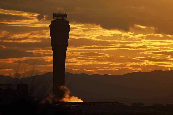 The sun rises behind the air traffic control tower at McCarran International airport, Thursday, March 19, 2020, in Las Vegas.  Officials at  the airport said in a tweet that it will remain open with reduced operations after an air traffic controller tested positive late Wednesday, temporarily closing the control tower.  (AP Photo/John Locher)