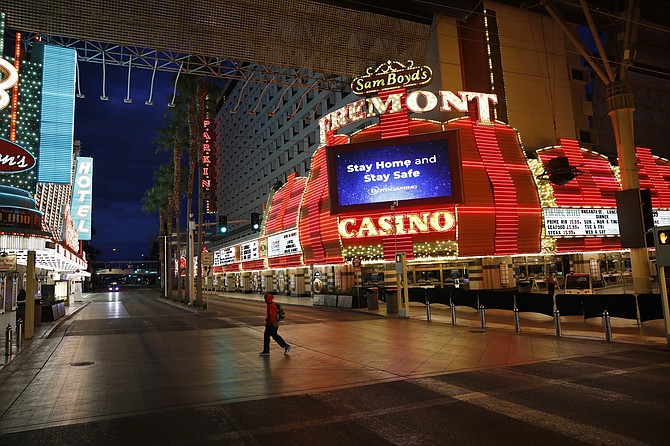 A man walks along a usually busy Fremont Street after casinos were ordered to shut down due to the coronavirus outbreak Saturday, March 21, 2020, in Las Vegas. 