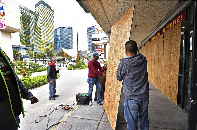 FILE - In this March 18, 2020, file photo, workers install plywood over windows at a souvenir shop along the Las Vegas Strip after all the casinos and non-essential businesses in the state were ordered to shut down due to the coronavirus in Las Vegas. The emerging coronavirus pandemic has spurred a lawsuit by a Las Vegas attorney with a background in big cases, who is seeking compensation from the Chinese government for more than 32 million small U.S. businesses that have lost income and profits as a result of the outbreak. Eglet seeks class-action status and said Tuesday, March 24, 2020 he believes damages for Chinese &quot;reckless&quot; and &quot;negligent&quot; conduct could be in the trillions of dollars. They seek compensation from the government of China. 