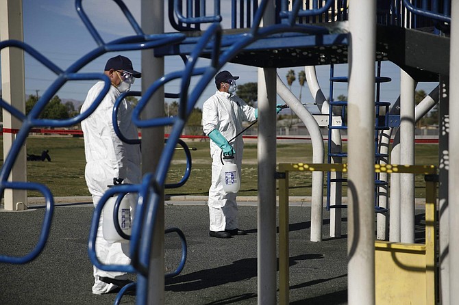 Workers clean and disinfect playground equipment due to the coronavirus outbreak at a park Wednesday, March 25, 2020, in Las Vegas. (AP Photo/John Locher)