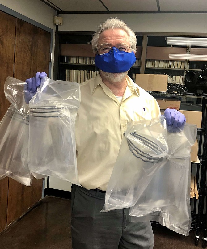Tod Colegrove, library director, holds up the plastic face shields, which are to users delivered inside sterile containers. 