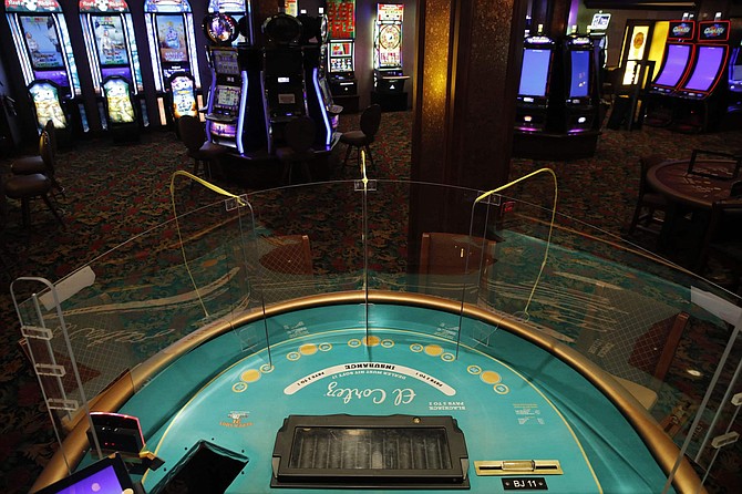 FILE - In this May 13, 2020, file photo, an acrylic gaming barrier is installed at a gaming table to protect people from the coronavirus at the El Cortez hotel and casino as it remains shuttered due to the coronavirus in Las Vegas. Nevada gambling regulators said Tuesday, May 26, 2020, they may require the state&#039;s shuttered casinos to test all &quot;front line&quot; resort workers for COVID-19, enact steps to prevent of the spread of illness and plan to isolate visitors and guests found to have the virus in order to get the OK to emerge from the coronavirus shutdown. 
