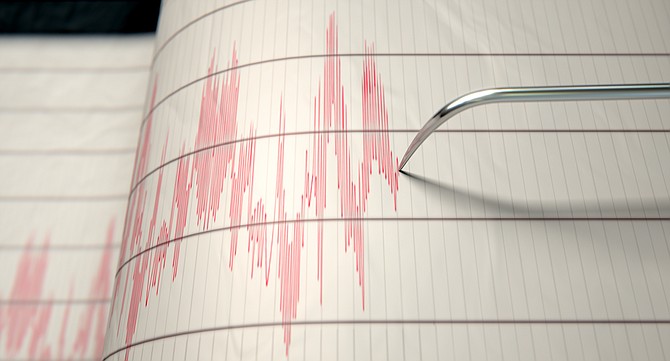A closeup of a seismograph machine needle drawing a red line on graph paper depicting seismic and eartquake activity - 3D render