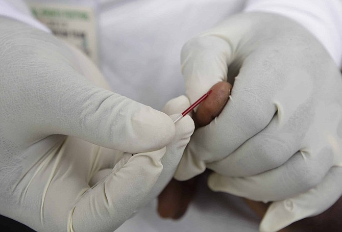 In this file photo from Dec. 1, 2012, a doctor takes a blood test from an athletes during the 18th National Sports Festival in Lagos, Nigeria.  The World Anti-Doping Agency is looking to artificial intelligence as a new way to detect athletes who cheat, it is revealed Tuesday May 26, 2020, funding four projects in Canada and Germany, looking at whether AI could spot signs of drug use. (AP Photo/Sunday Alamba, FILE)
