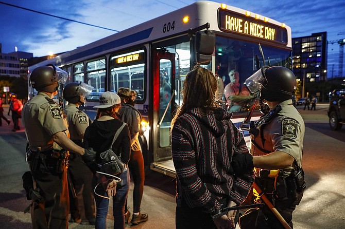 Arrested protesters are loaded onto a transport bus by police on South Washington Street, Sunday, May 31, 2020, in Minneapolis. Protests continued following the death of George Floyd, who died after being restrained by Minneapolis police officers on Memorial Day. (AP Photo/John Minchillo)