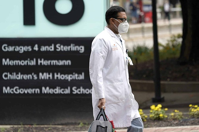 A healthcare professional walks through the Texas Medical Center Thursday, June 25, 2020, in Houston. The leaders of several Houston hospitals said they were opening new beds to accommodate an expected influx of patients with COVID-19, as coronavirus cases surge in the city and across the South. 
