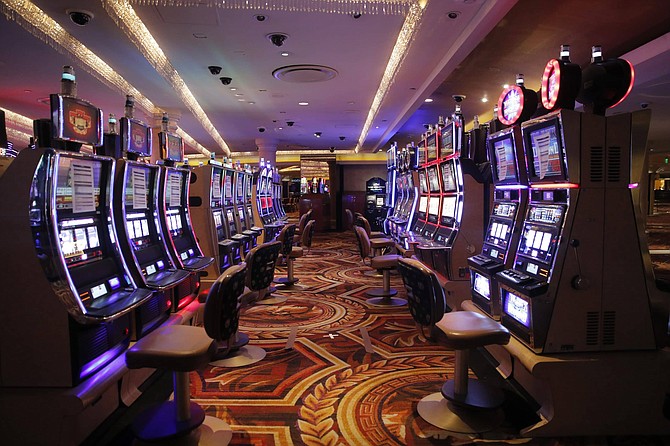 FILE - In this May 21, 2020, file photo, chairs have been removed at some electronic slot machines to maintain social distancing between players at a closed Caesars Palace hotel and casino in Las Vegas. Casinos from Lake Tahoe to Laughlin are announcing plans to reopen June 4, and a downtown Las Vegas hotel owner bought more than 1,000 one-way airline tickets for people from various U.S. cities. Nightlife will be limited, but promotions began Wednesday, May 27, 2020, after Nevada Gov. Steve Sisolak lifted his mid-March shut-down order and said casinos can reopen June 4. (AP Photo/John Locher, File)