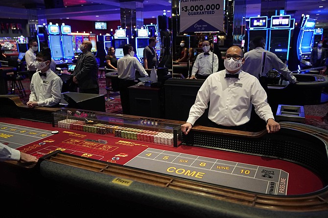 Dealers in masks wait for customers before the reopening of the D Las Vegas hotel and casino, Wednesday, June 3, 2020, in Las Vegas. Casinos were allowed to reopen on Thursday after temporary closures as a precaution against the coronavirus. 