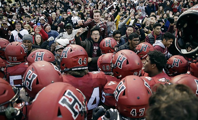 FILE - In this Nov. 17, 2018, file photo, Harvard players, students and fans celebrate their 45-27 win over Yale after an NCAA college football game at Fenway Park in Boston. The Ivy League has canceled all fall sports because of the coronavirus pandemic. 