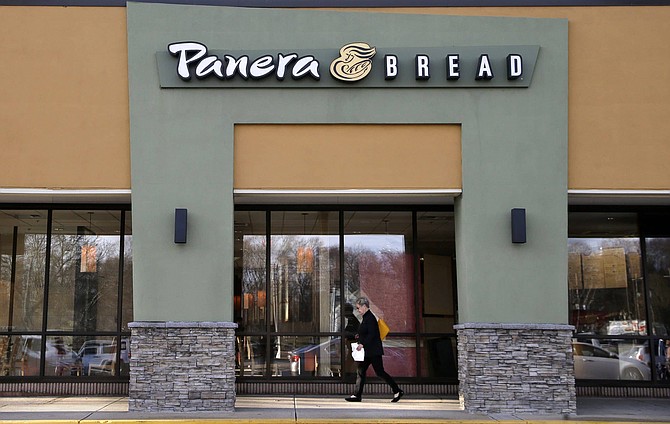 FILE - In this Wednesday, April 12, 2017, file photo, a passer-by walks near an entrance to a Panera Bread restaurant in Natick, Mass. In a deal announced Wednesday, Nov. 8, 2017, Panera Bread says it is buying bakery chain Au Bon Pain to boost its presence in airports, hospitals and colleges. (AP Photo/Steven Senne, File)