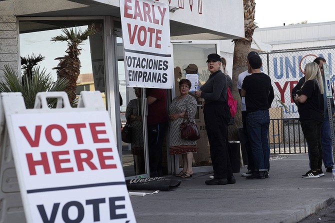 FILE - In this Feb. 15, 2020 file photo, people wait in line at an early voting location at the culinary workers union hall in Las Vegas. Nevada is attempting a high-wire act of holding its first-ever election almost entirely by mail, reflecting a new law allowing voters to register at the polls while keeping people safe amid the pandemic. Secretary of State Barbara Cegavske limited the number of polling places for the Tuesday, June 9, 2020, primary and instead sent absentee ballots to voters. 