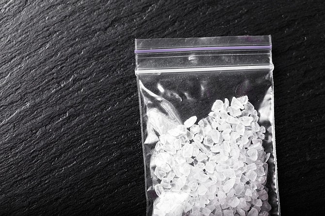 drugs in the form of crystals on a black background, methamphetamine in a plastic bag