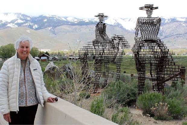 Mary Fischer stands beside the depiction of ranchers overlooking their property at the E. Fifth Street bridge in this file photo. The overpass depicts the history of the early ranchers.