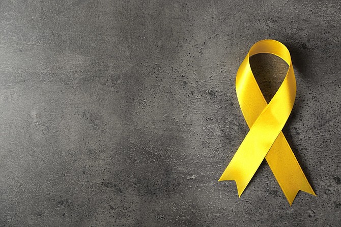 Yellow awareness ribbon on grey textured background