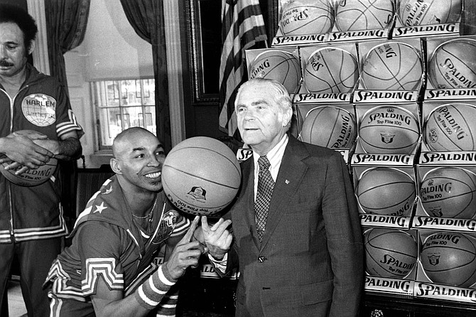FILE - In this Feb. 15, 1977, file photo, the Harlem Globetrotters&#039; Fred &quot;Curly&quot; Neal of shows New York City Mayor Abe Beame the art of balancing a basketball on a finger during ceremony at City Hall. Neal, the dribbling wizard who entertained millions with the Harlem Globetrotters for parts of three decades, has died the Globetrotters announced Thursday, March 26, 2020. He was 77. Neal played for the Globetrotters from 1963-85, appearing in more than 6,000 games in 97 countries for the exhibition team known for its combination of comedy and athleticism. 