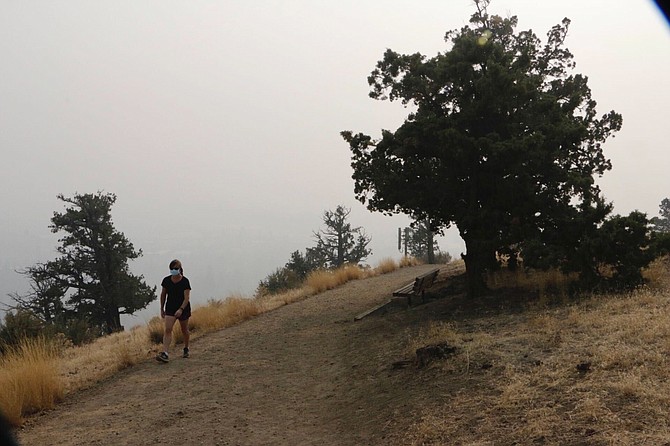 A woman walks up a trail on Pilot Butte, a lava dome overlooking the city of Bend, Ore., Tuesday, Sept. 15, 2020. Wildfires have created hazardous air quality in Bend and other cities across the U.S. West. (AP Photo/Rachel La Corte)