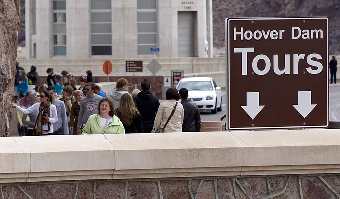 FILE - In this April 8, 2011, file photo, tourists approach the visitor center at Hoover Dam near Boulder City, Nev. Officials say there will be fewer Hoover Dam tours starting next month as work begins on renovations to the visitor center and guest elevators at the iconic structure. The U.S. Bureau of Reclamation, which operates the dam, announced Tuesday, Aug. 28, 2018, that the construction will begin Oct. 1 and continue for about four months. (AP Photo/Julie Jacobson, File)