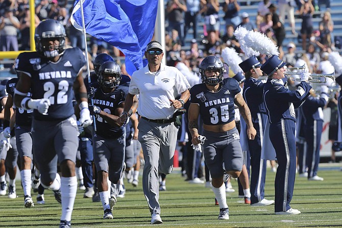 Nevada coach Jay Norvell, center, leads his team onto the field to face Weber State for an NCAA college football game in Reno, Nev., Saturday, Sept. 14, 2019. 